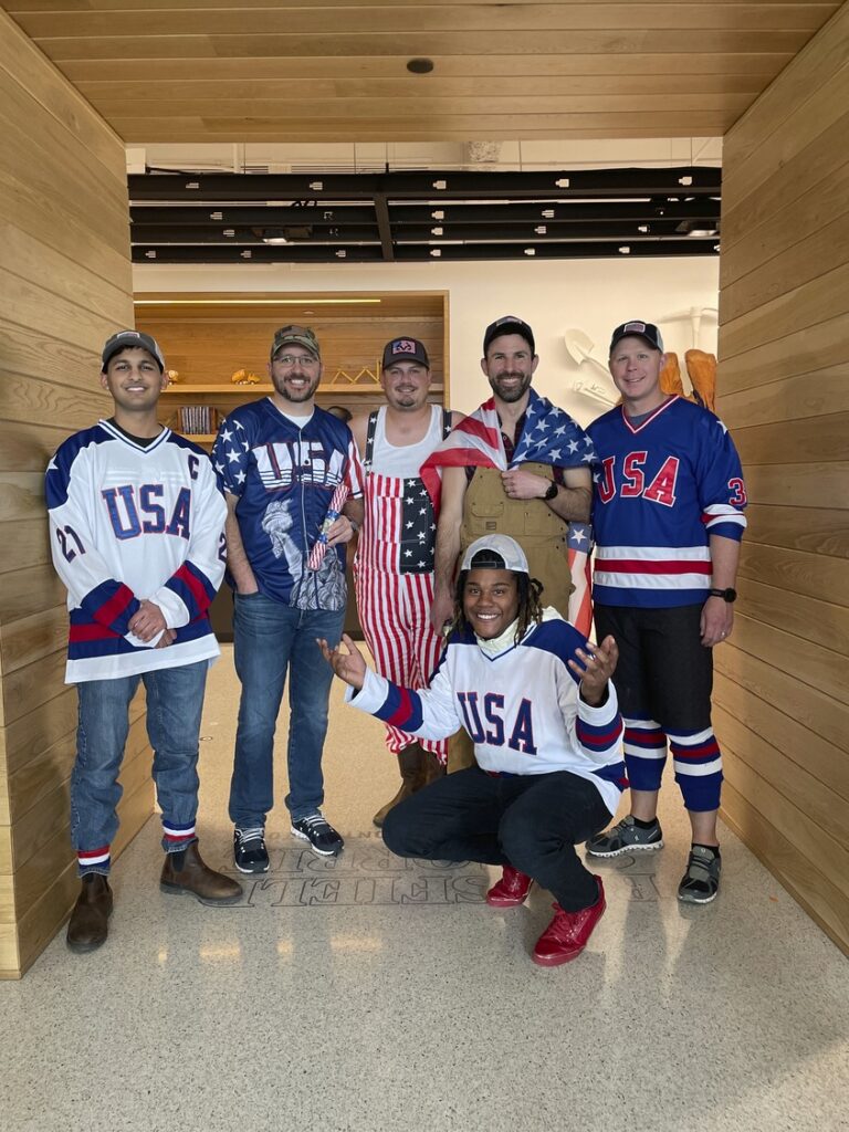 A group of six individuals dressed in various usa-themed sports attire posing for a photo.
