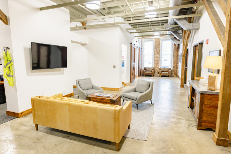 Modern office waiting area with comfortable seating and industrial design elements.