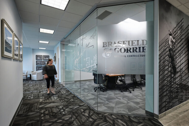 A person walks through a modern office corridor in Jackson, Mississippi, with glass walls and the company name 