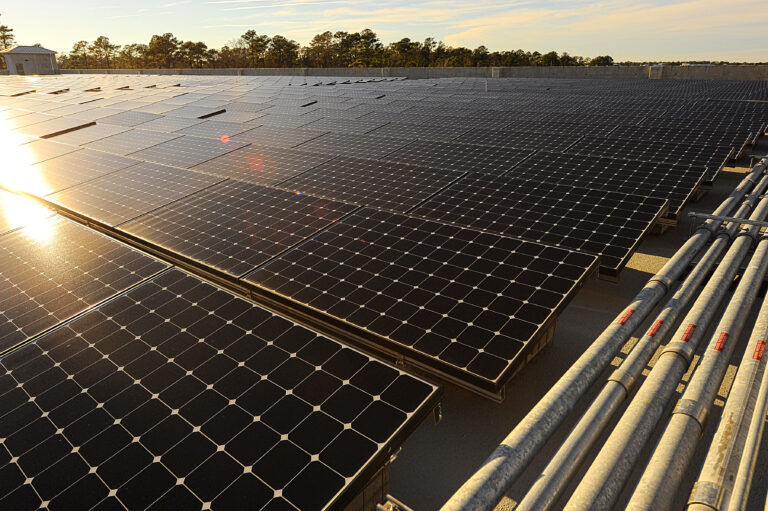 Expansive solar panel array basking in the sunlight with electrical conduits in the foreground.