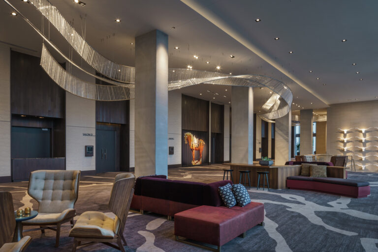An elegant and modern hotel lobby featuring curved lighting fixtures, stylish seating areas, contemporary decor, and designed to meet the highest standards of the hospitality industry.