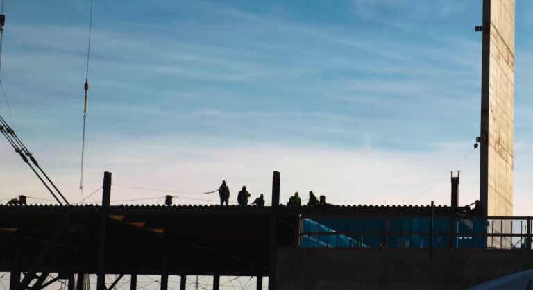 Construction workers on a building site at dawn or dusk.