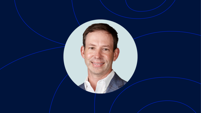 Jason Weeks, dressed in a suit, poses for a headshot against a light blue background, accentuated by a striking dark blue circular pattern.