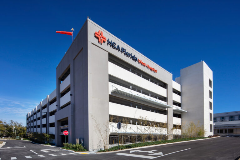 The exterior view of a multi-story hospital parking garage under a clear blue sky.