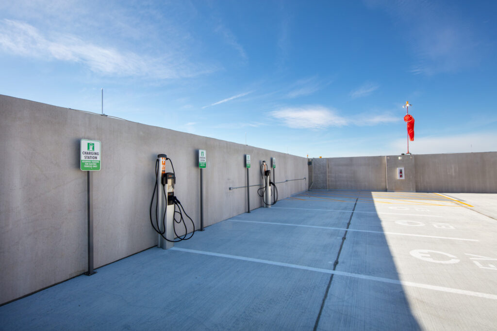 The recently completed parking deck at HCA Florida West features electric vehicle charging stations on the top level. A clear blue sky is visible.